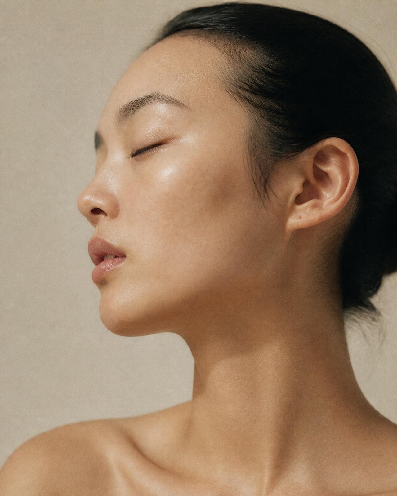 Editorial portrait of luminous, bare skin in soft daylight
